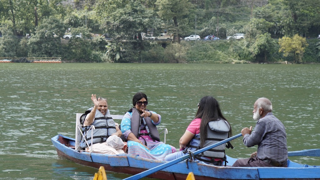 Guests smiling and waving from a boat on a hill-station lake